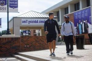 Photo of student guiding other student for direction on campus.